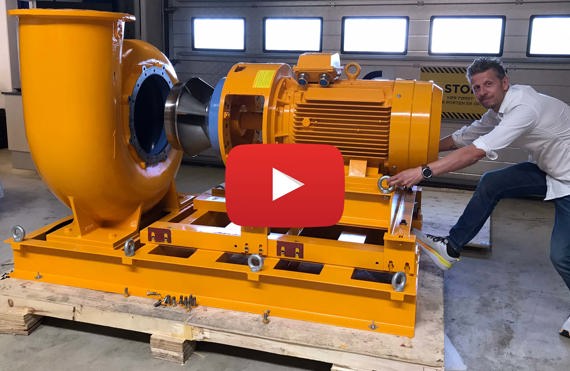 Man adjusting large yellow DESMI pump in an industrial setting.